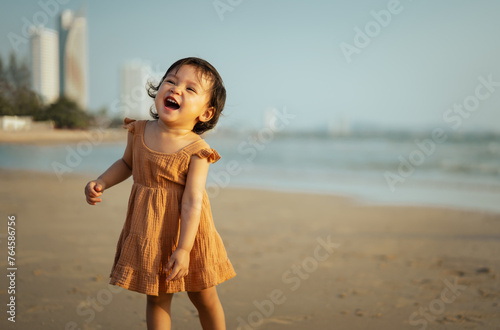 cheerful toddler baby girl laughing while standing on sea beach © geargodz