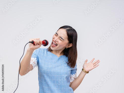 Enthusiastic Asian woman enjoying singing into a microphone, karaoke fun isolated on white