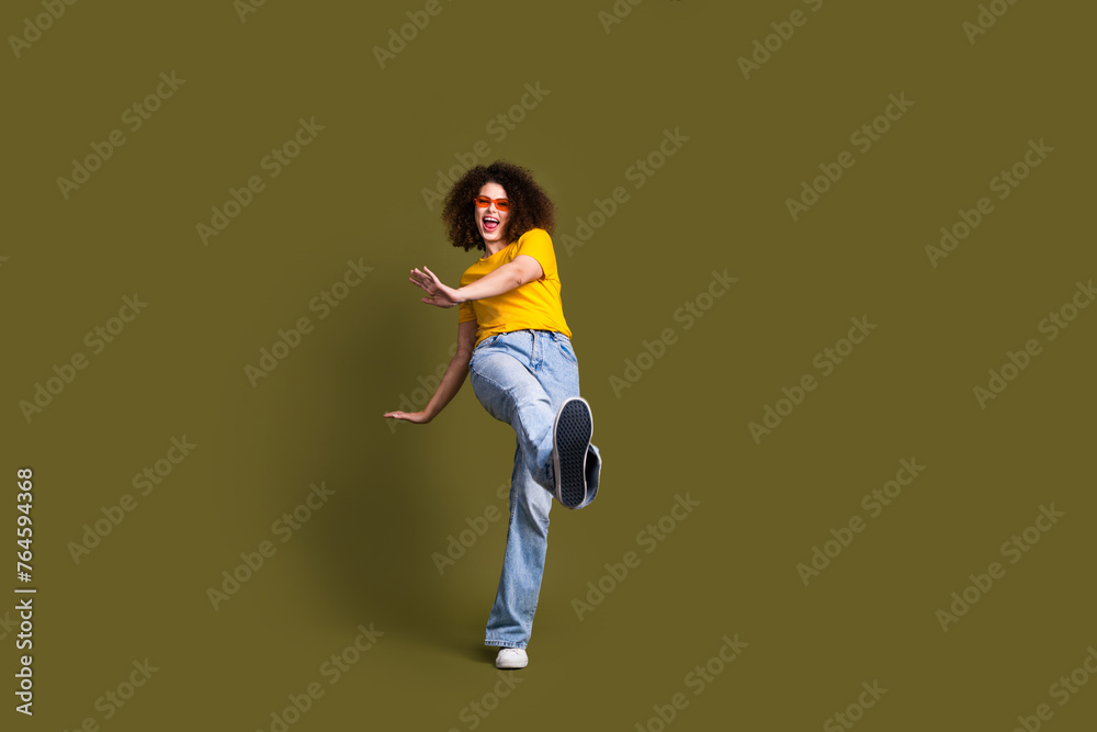 Full body size photo of millennial woman in stylish outfit chilling step toward sneakers sole brand ad isolated on khaki color background Full body size photo of millennial woman in stylish outfit chilling step toward sneakers sole brand ad isolated on khaki color background