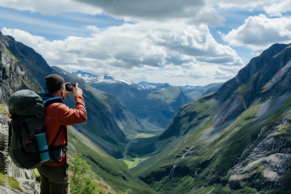 hiker taking photo of valley from high vantage point