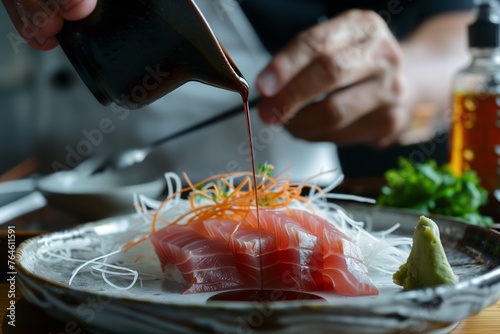 cook drizzling soy sauce over a sashimi piece