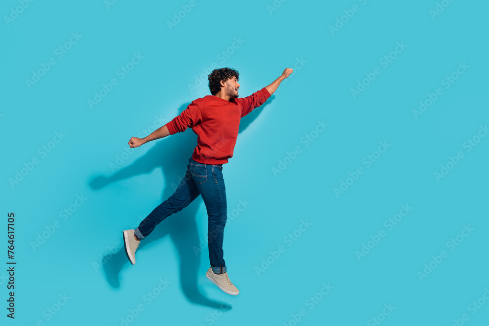 Full body size photo of active sportive superhero guy jumping fist up motivated flying to future isolated on aquamarine color background