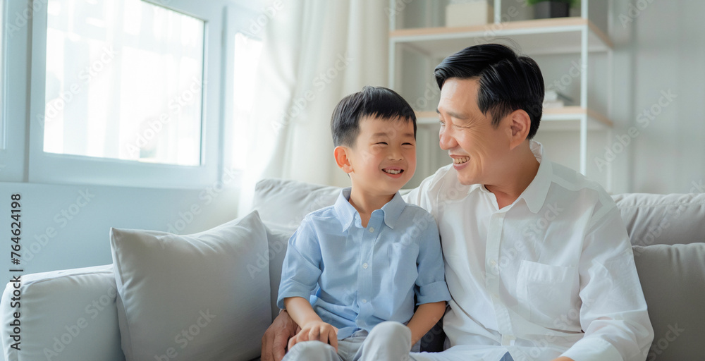 Portrait of father and son. Asian middle age male with boy, smiling and happy sitting indoor. Father's Day concept.