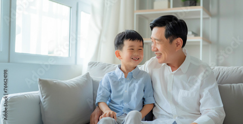 Portrait of father and son. Asian middle age male with boy, smiling and happy sitting indoor. Father's Day concept.