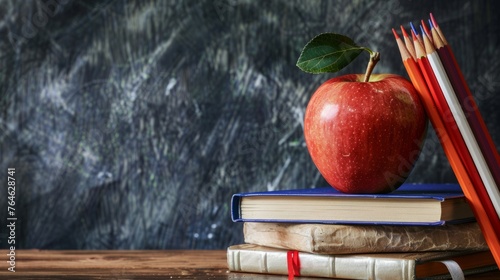 back to school: apple sitting atop a stack of books surrounded by supplies and stationery photo