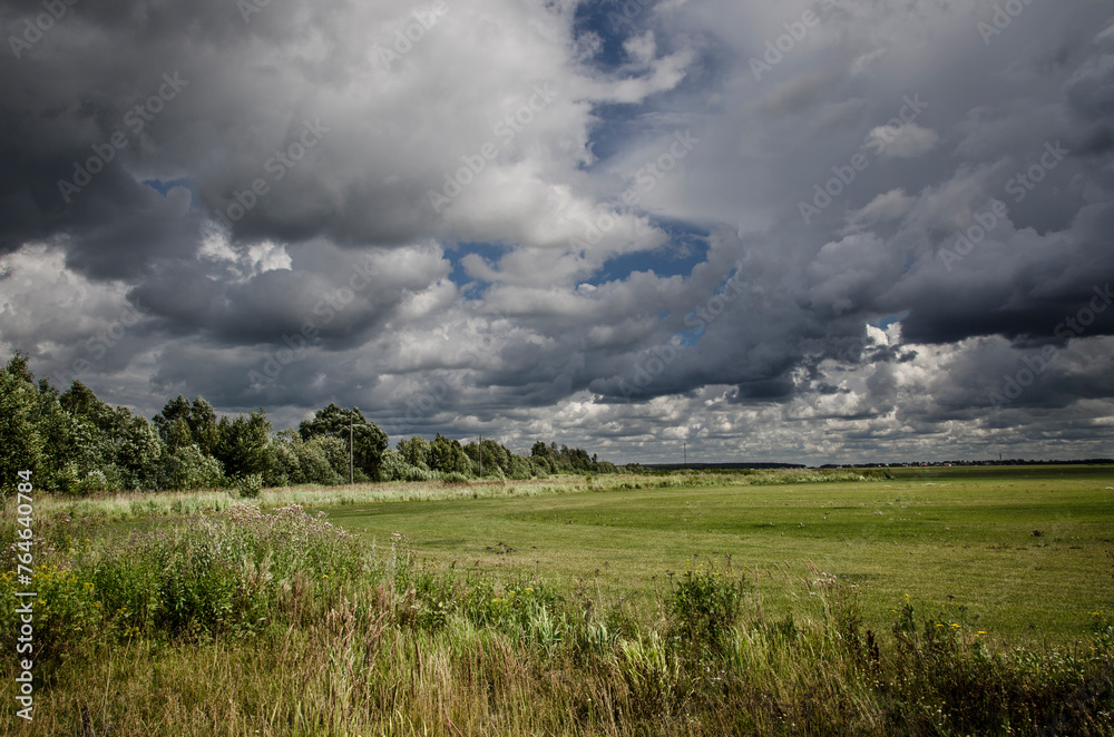 summer landscape with green meadow and dark clouds in the sky summer landscape with green meadow and dark clouds in the sky