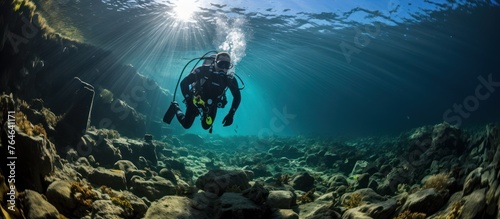 a diver with full scuba equipment performs in the deep blue sea photo