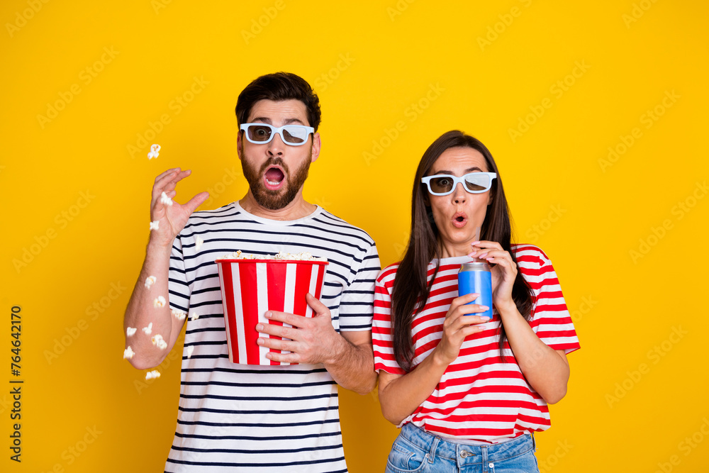 Obraz premium Portrait of frightened impressed people watch scary movie 3d glasses hold soda drink cup throw popcorn isolated on yellow color background
