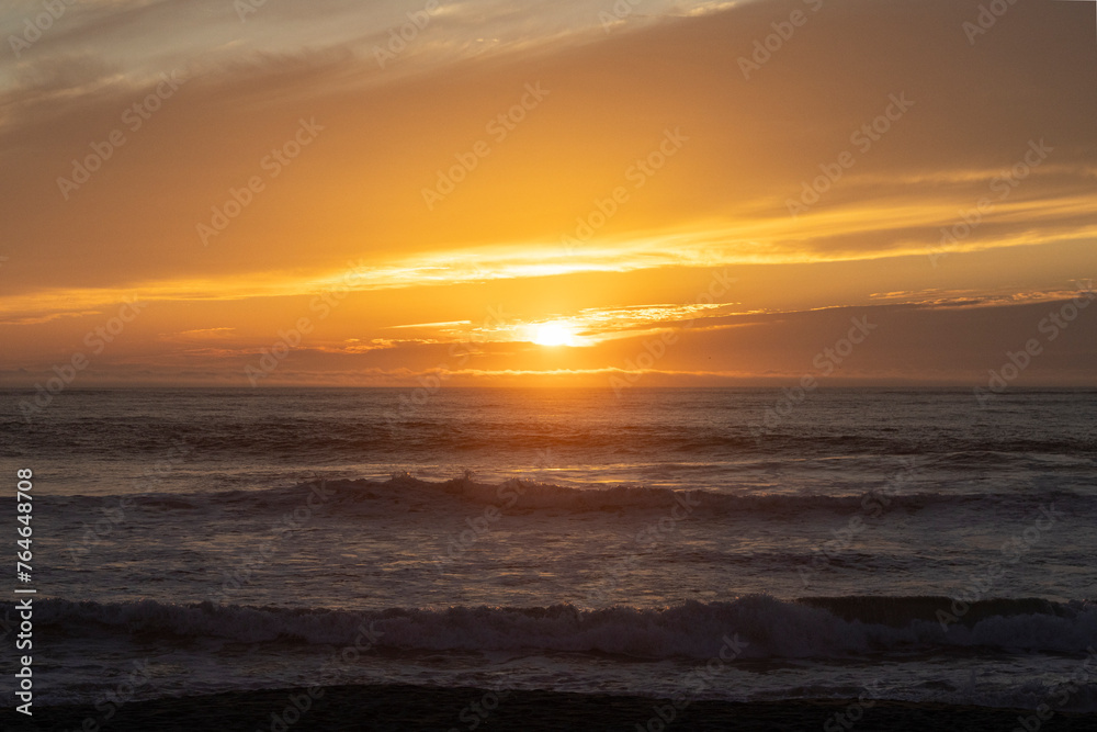 Sea with waves and a beautiful sunset on Espinho beach in Portugal. Yellow and orange sky.