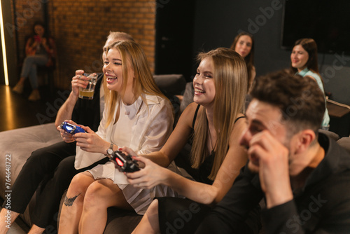 Women laugh playing console with level of focus and determination. Players and spectators became fully immersed in gaming experience