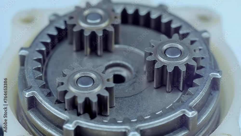 Speed reducer motor with many rotating metal gears shining in the light. Closeup. Macro Speed reducer motor with many rotating metal gears shining in the light. Closeup. Macro