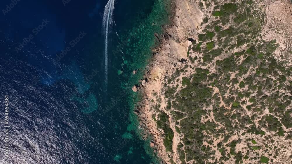 Boat driving along cliffs over crystal clear water top down drone shot Boat driving along cliffs over crystal clear water top down drone shot