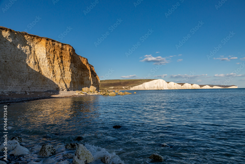 A view of the chalk Seven Sisters cliffs on the Sussex coast, with a blue sky overhead