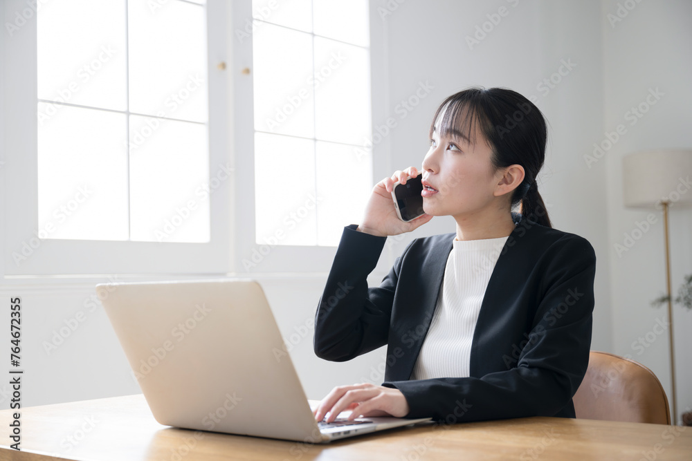 Woman in a business setting on the phone while operating a computer. Woman in a business setting on the phone while operating a computer.