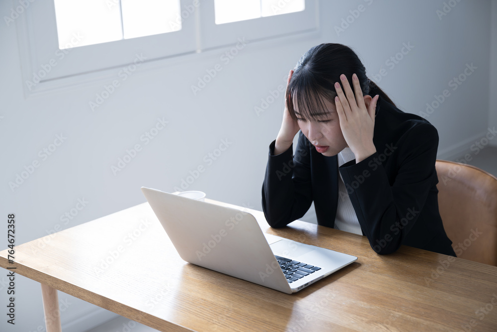Young businesswoman working on a computer, looking at the screen and worrying about her head. Young businesswoman working on a computer, looking at the screen and worrying about her head.