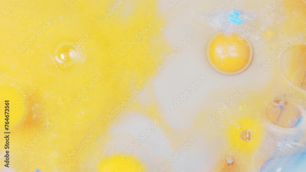Vibrant ink drops swirling in water, creating abstract yellow and blue patterns Vibrant ink drops swirling in water, creating abstract yellow and blue patterns
