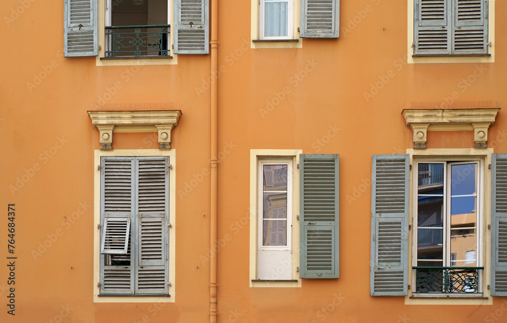 Obraz premium France. Cannes. Beautiful wooden windows with shutters. Beautiful wooden window shutters with window sill, orange cement wall on a sunny day
