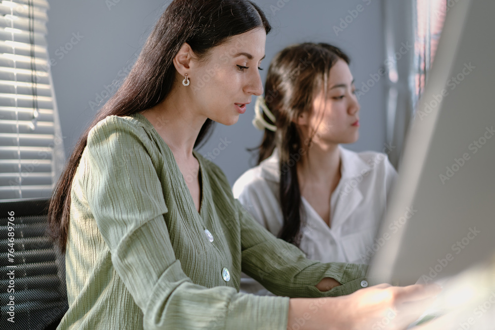 Female apprentice learning business from caucasian businesswoman in office. Professional manager teaching training young Asian trainee. Confident mentor instructor and intern talking in workplace Female apprentice learning business from caucasian businesswoman in office. Professional manager teaching training young Asian trainee. Confident mentor instructor and intern talking in workplace