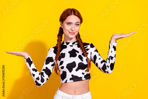 Photo of doubtful thoughtful lady dressed cowskin top comparing arms empty space isolated yellow color background © deagreez