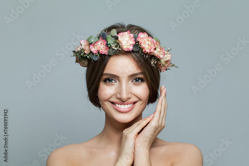 Beautiful model woman with fresh clear skin smiling on gray background. Facial treatment, skincare and cosmetology concept