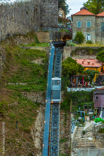 Aerial view of the Guindais Funicular going up the rails of the hill with its picturesque houses and tourists sitting on the terrace of a bar in the historic center of the city of Porto. photo