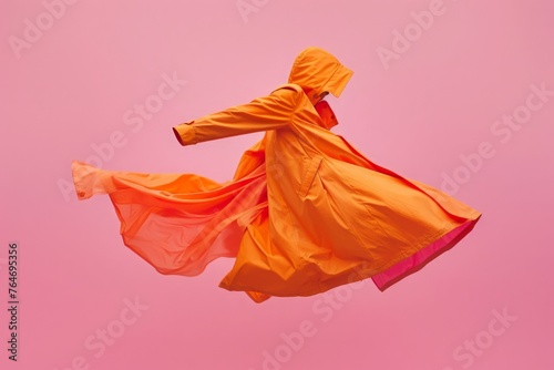 A captivating orange coat appears suspended mid-dance, exuding both warmth and style amid a soft pink canvas. photo