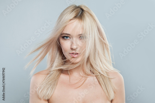 Blond woman face close-up. Blonde model with fresh clear skin and healthy silky hair on white background