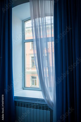 A window with blue curtains and a beautifully falling tulle.
