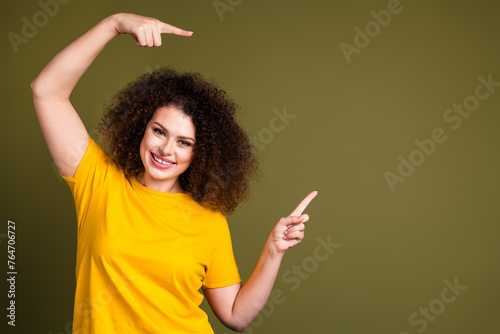 Portrait of young charming woman pointing fingers rebranding her company wearing yellow uniform isolated on khaki color background © deagreez