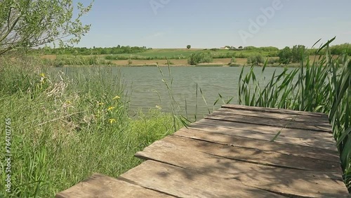 Wooden raft on a lake Moharac surrounded with green reeds and wildflowers photo