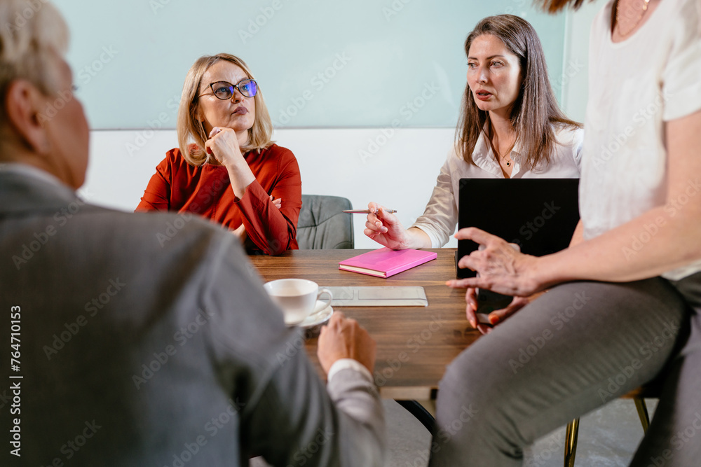 Office colleagues having casual discussion during meeting in conference room. Group of women sitting in conference room and talking. Office colleagues having casual discussion during meeting in conference room. Group of women sitting in conference room and talking.
