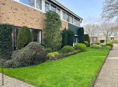 Front yard landscaping with evergreens and green lawn. Maintenance-free garden. Terborg. Netherlands photo