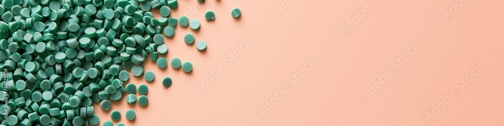 collection of green recycled plastic pellets on a peach background ...