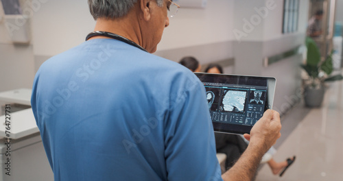 Tableau sur toile Backview Shot of Indian Doctor Walking in Hospital Corridor, Using a Digital Tablet
