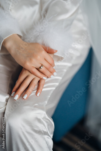 without a face. Female hands with wedding ring on leg in silk pajamas. 