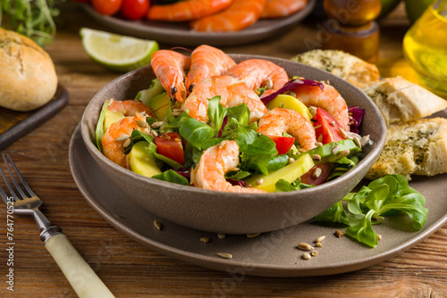 Spring salad with shrimp, mango and avocado. Served in a bowl, with croutons, sprinkled with roasted sunflower seeds.