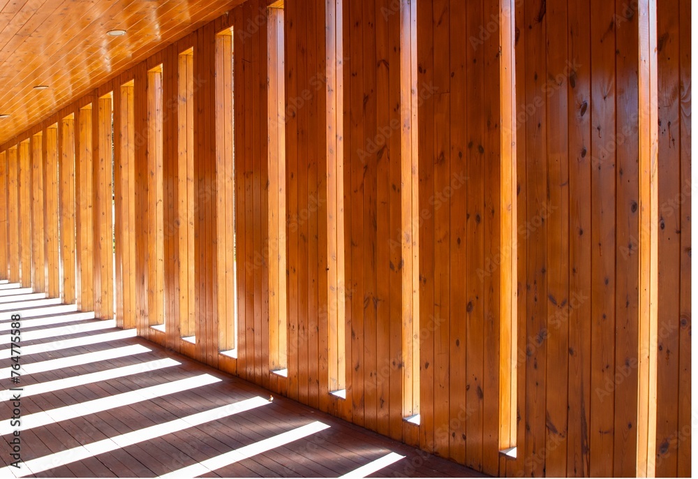 Lights and shadows in the hallway. Wall of planks with symmetrical distances where sunlight penetrates Lights and shadows in the hallway. Wall of planks with symmetrical distances where sunlight penetrates