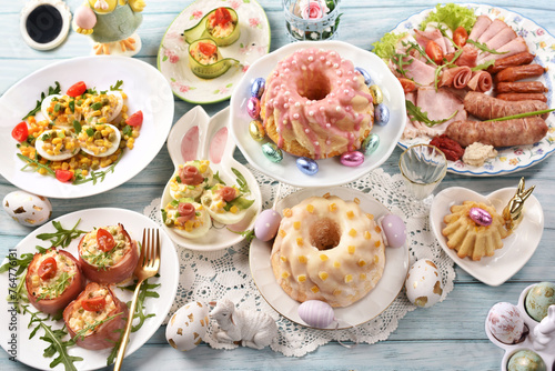 Traditional Easter breakfast with salads, deviled eggs, cold cuts and pastries on blue wooden table