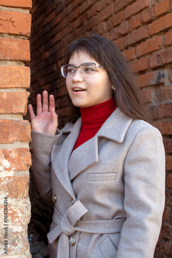A woman in a gray coat standing between two brick walls	