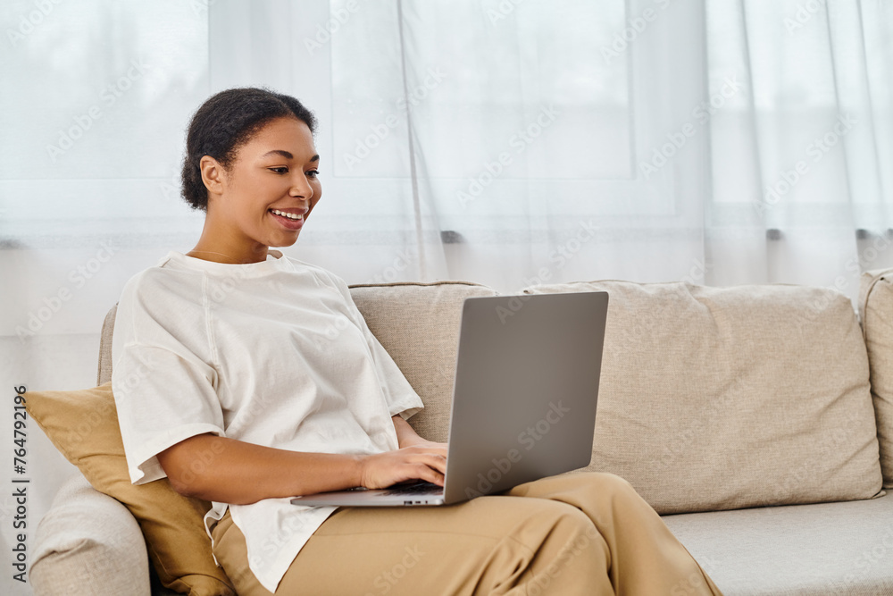 happy african american nutritionist using laptop while working from home in living room happy african american nutritionist using laptop while working from home in living room