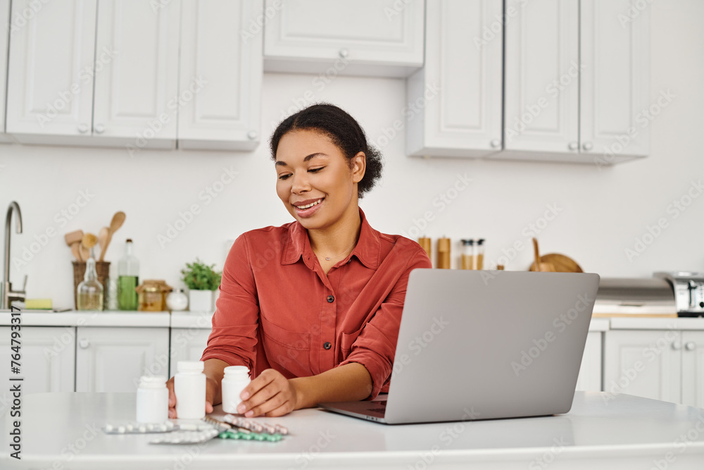 happy nutritionist looking at bottles with different medication during online consultation on laptop happy nutritionist looking at bottles with different medication during online consultation on laptop
