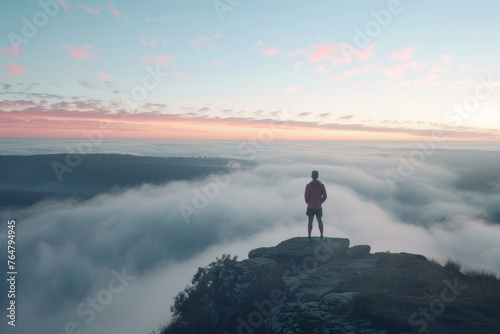A man is standing on a mountain peak, high above the clouds, with a vast fog-covered landscape below him