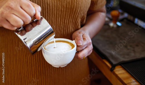 Barista pouring milk into coffee making a cappuccino. Barista making cappuccino,Professional bartender preparing coffee drink