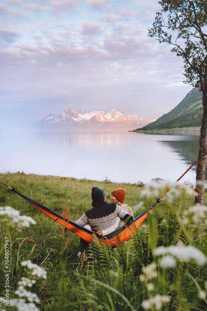 Couple in love chilling in hammock man and woman traveling together summer vacations friends on camping trip outdoor in Norway family lifestyle boyfriend and girlfriend hugging romantic feelings - obrazy, fototapety, plakaty 