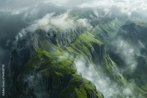 Cinematic shot of the view from above, looking down at an epic mountain range with clouds rolling over and mist hanging in between mountains, green grass on cliffs
