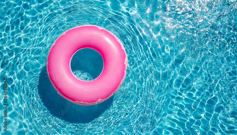 Fototapeta premium Pink inflatable ring floating in swimming pool water, summer holiday concept
