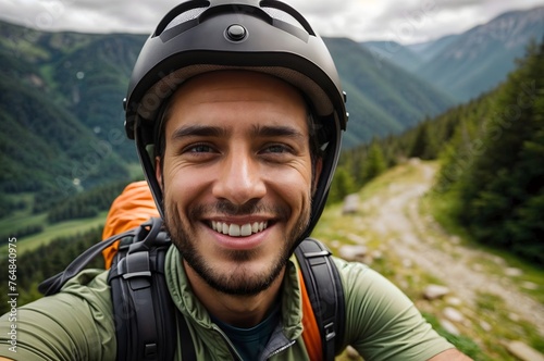 Young male cyclist takes selfie on top of mountain, young biker smiling, tourism and travel 