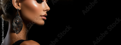 Sexy strict woman with black dress, tan skin, makeup and a fashionable hairstyle poses in studio on black background, with copyspace, blank space for text. Black friday shopping design concept