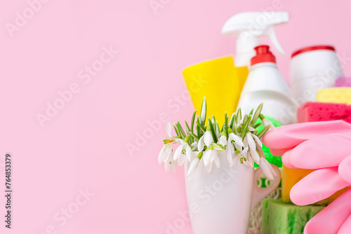 Spring flowers, detergents and cleaners for cleaning the house on a pink background. Spring cleaning. Copy space. Close-up.