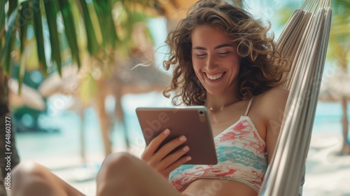 Woman on a sun lounger at the beach is using a tablet